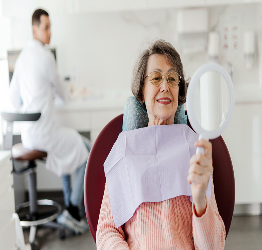 Patient, senior, mature woman holding mirror, looking, talking to senior professional dentist