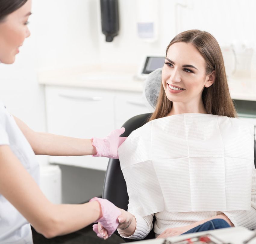 A woman sitting in a dental chair, smiling, during her visit to an oral surgeon in Boulder, CO.