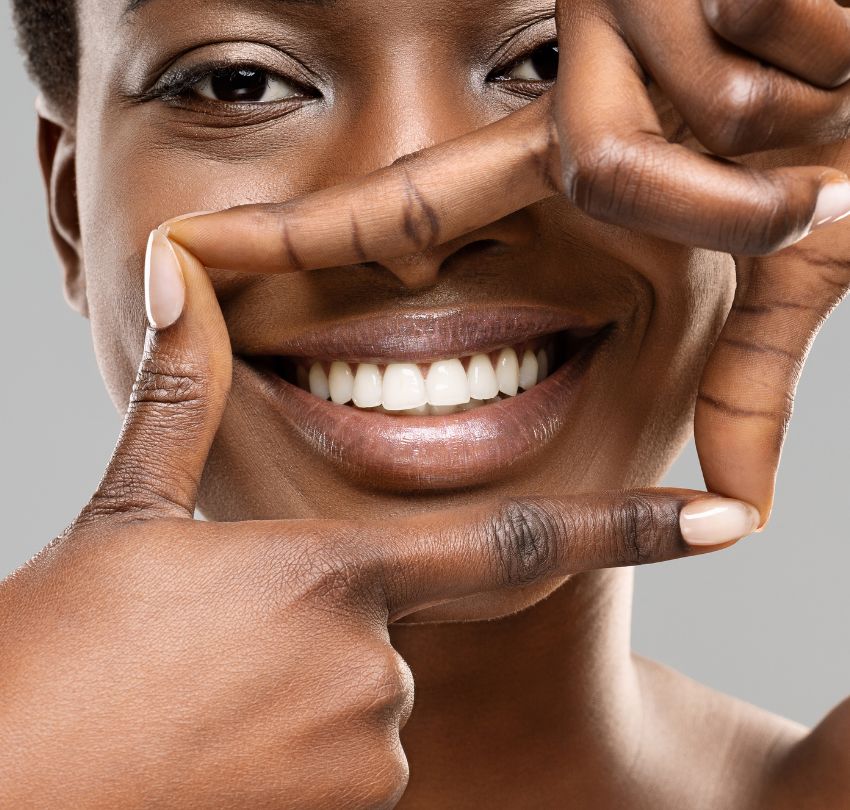 Beautiful black woman framing her healthy white teeth with fingers