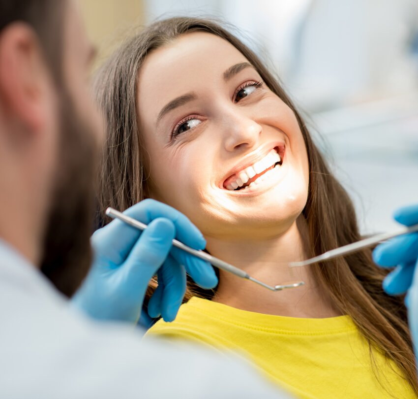 Portrait of a woman with toothy smile sitting during examination at the dental office